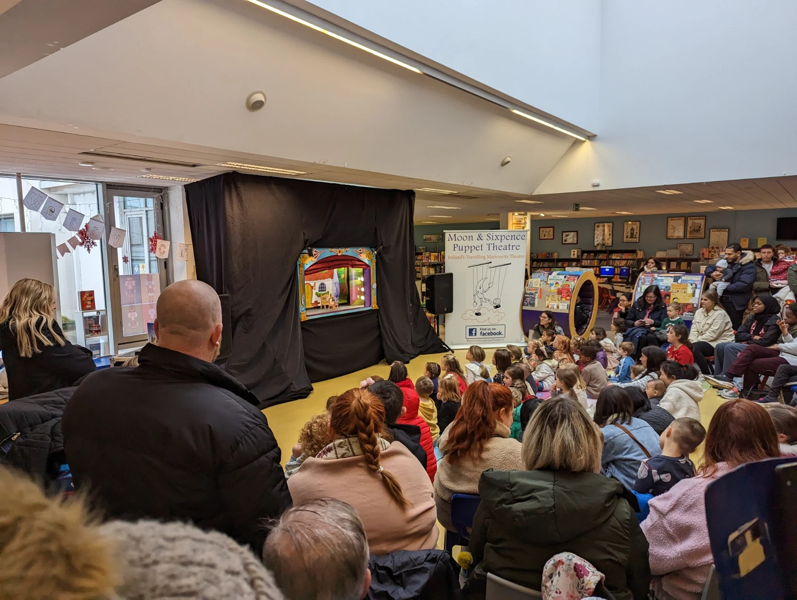 Children watching a Moon & Sixpence marionette performance in a library.